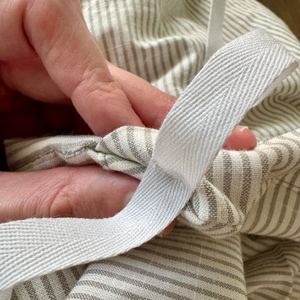 A single example of a strip sewn into a green striped duvet cover, with the stitches visible.