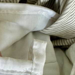 A close-up photograph of a loop on a weighted blanket, against the backdrop of a stripy green and white duvet cover.